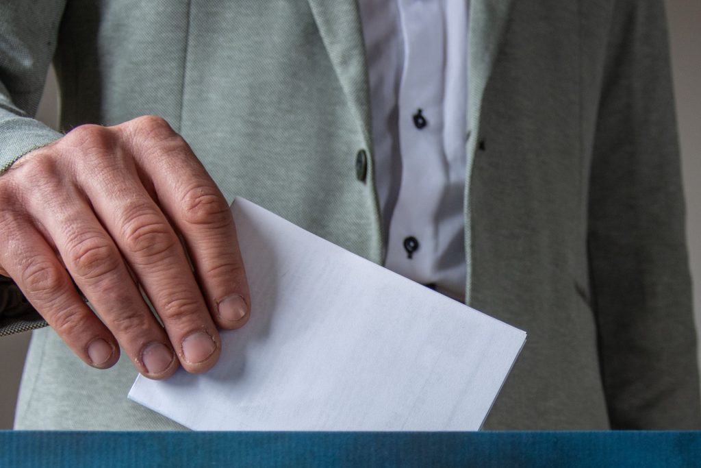 A man putting a ballot in an election box.