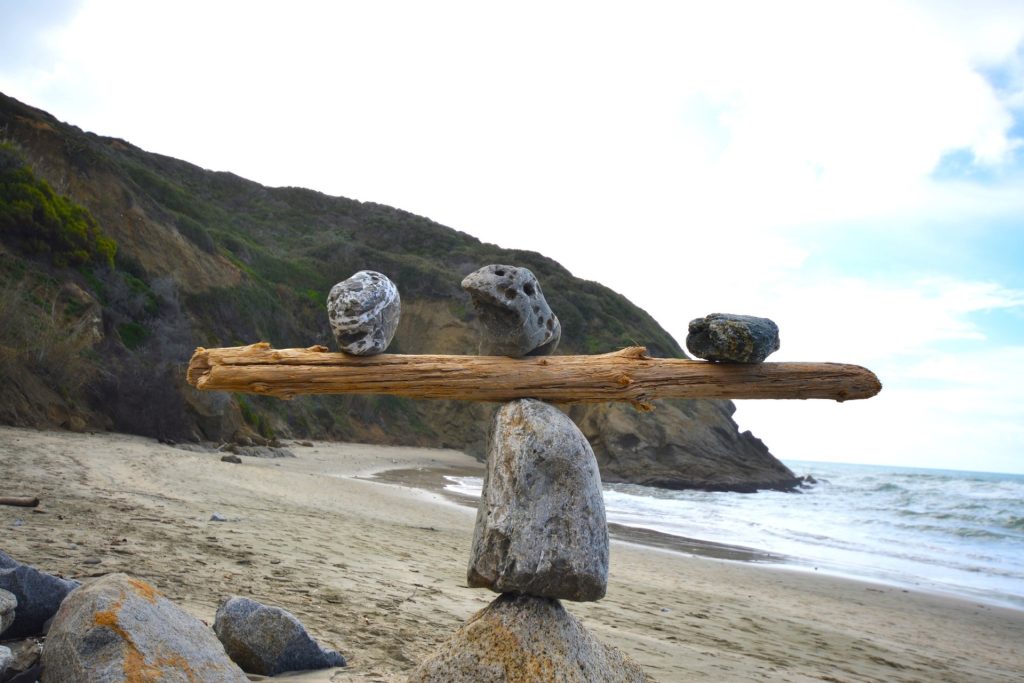 Rocks balancing on log on top of another rock